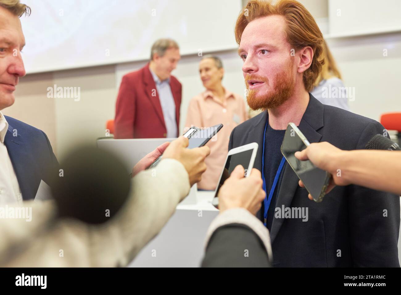 Geschäftssprecher, der auf einer Pressekonferenz mit Journalisten mit Mikrofonen und Telefonen spricht Stockfoto