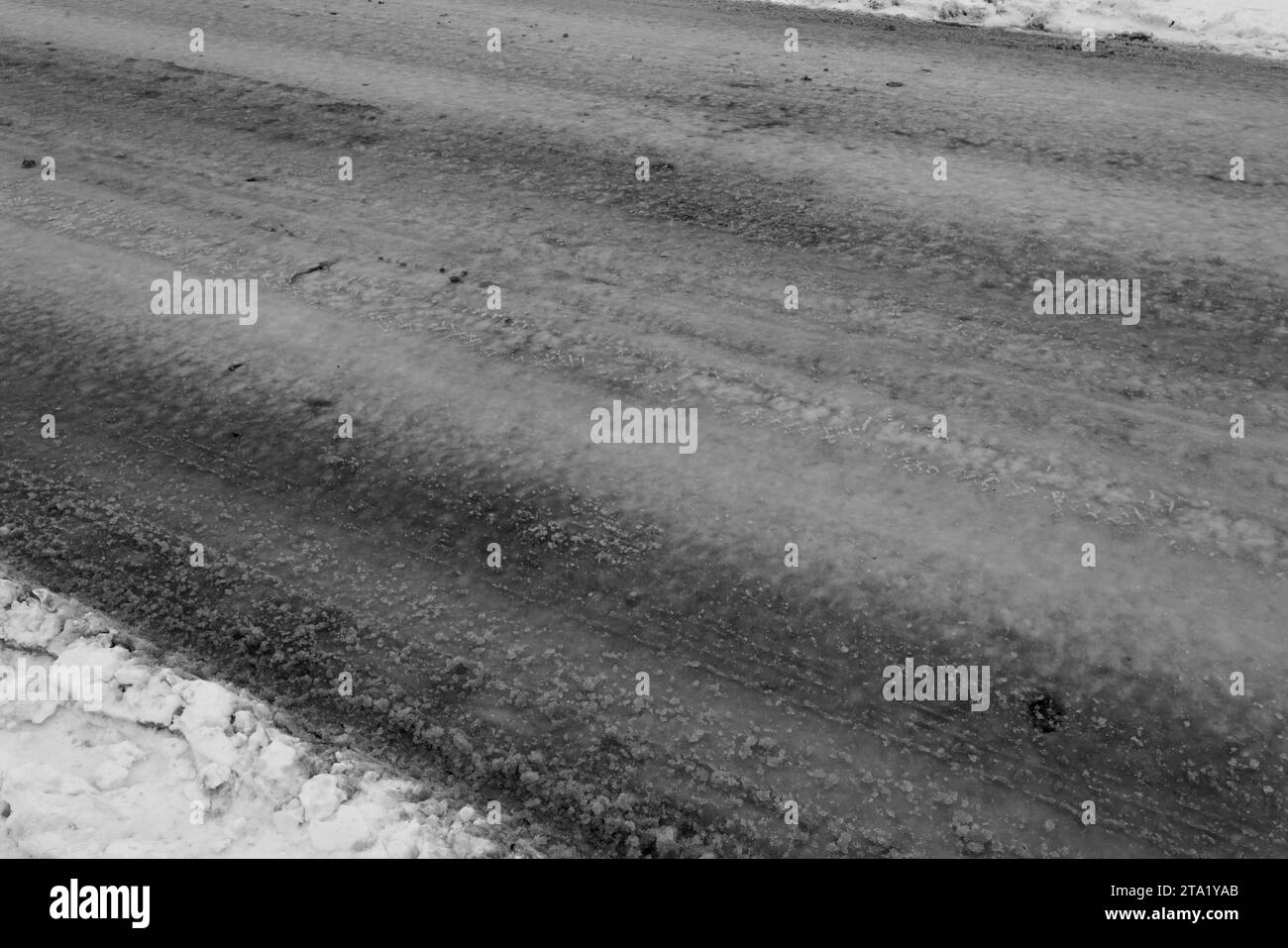 Verschneite Straße auf dem Land. Driftet auf einer unbepflügten, schneebedeckten Landstraße durch Cottage Community. Autospuren im Winter. Das Konzept des gefährlichen Drivi Stockfoto