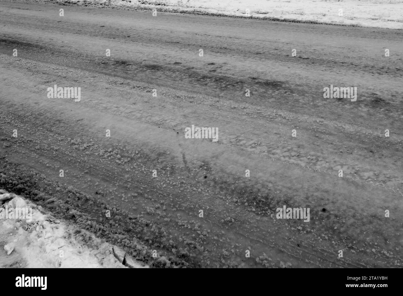 Verschneite Straße auf dem Land. Driftet auf einer unbepflügten, schneebedeckten Landstraße durch Cottage Community. Autospuren im Winter. Das Konzept des gefährlichen Drivi Stockfoto