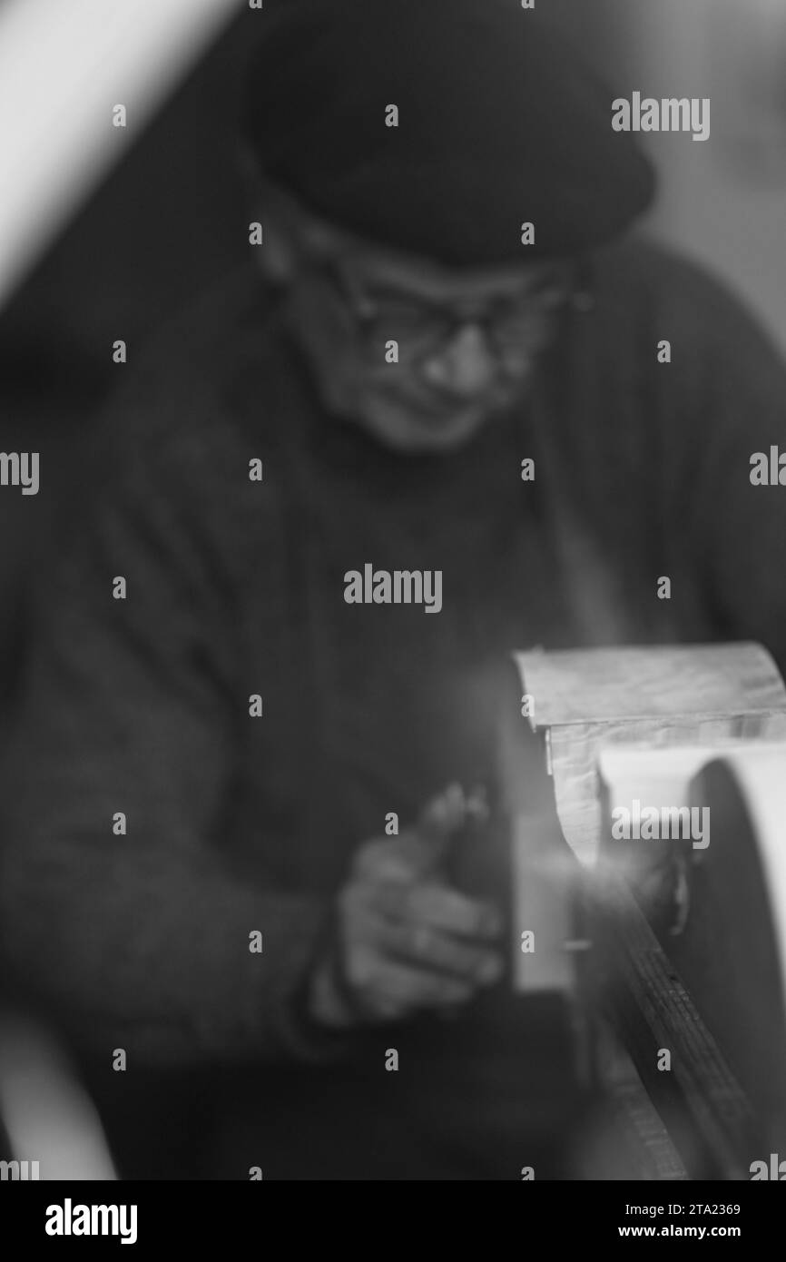 Erfahrener Geigenbauer schnitzt in der Werkstatt Cremona Italien, selektiver Fokus, Bokeh Stockfoto