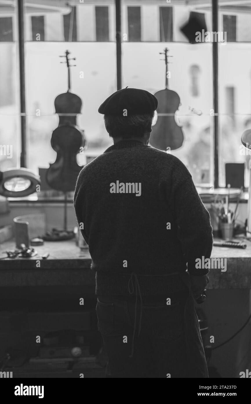 Ein erfahrener Geigenbauer schnitzt in der Werkstatt Cremona Italy, monochrome Keilrippen eines neuen klassischen Cellomodells Stockfoto