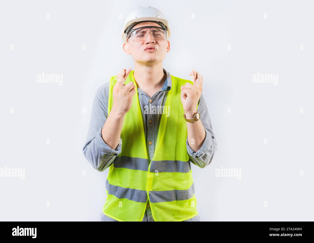 Porträt eines jungen Ingenieurs, der sich wünscht. Ein hübscher Ingenieur, der die Finger drückt und sich einen Wunsch wünscht Stockfoto