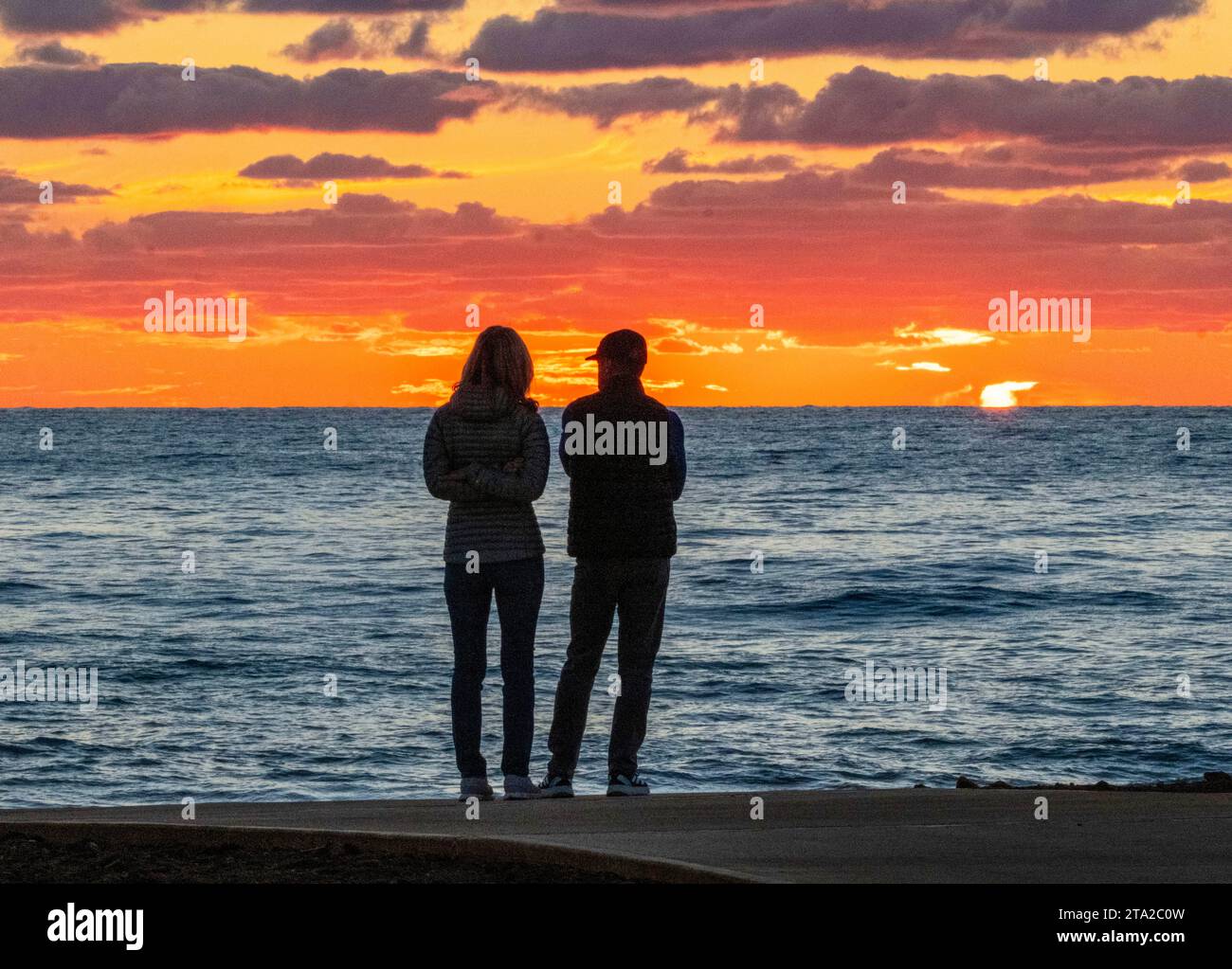 Ein junges Paar beobachtet den Sonnenuntergang über dem Mittelmeer, Paphos, Zypern Stockfoto
