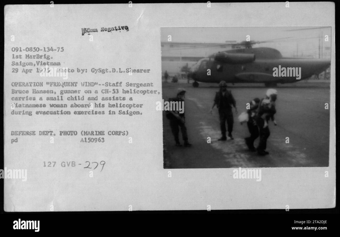 Staff Sergeant Bruce Hansen, CH-53 Helikopter-Schütze, unterstützt eine vietnamesische Frau und ein Kind während des 29. April 1975 bei Evakuierungsübungen in Saigon im Rahmen der Operation Frequent Wind. Stockfoto