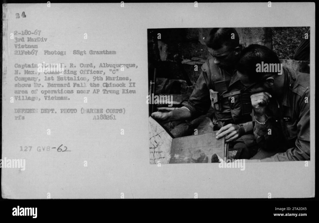 Captain James H. R. Curd, Befehlshaber der C-Kompanie, 1. Bataillon, 9. Marines, zeigt Dr. Bernard Fall das Einsatzgebiet Chinook II in der Nähe von AP Trung Kieu Village, Vietnam. Dieses Bild wurde am 21. Februar 1967 im Rahmen von Briefings während militärischer Aktivitäten in Vietnam aufgenommen. Stockfoto