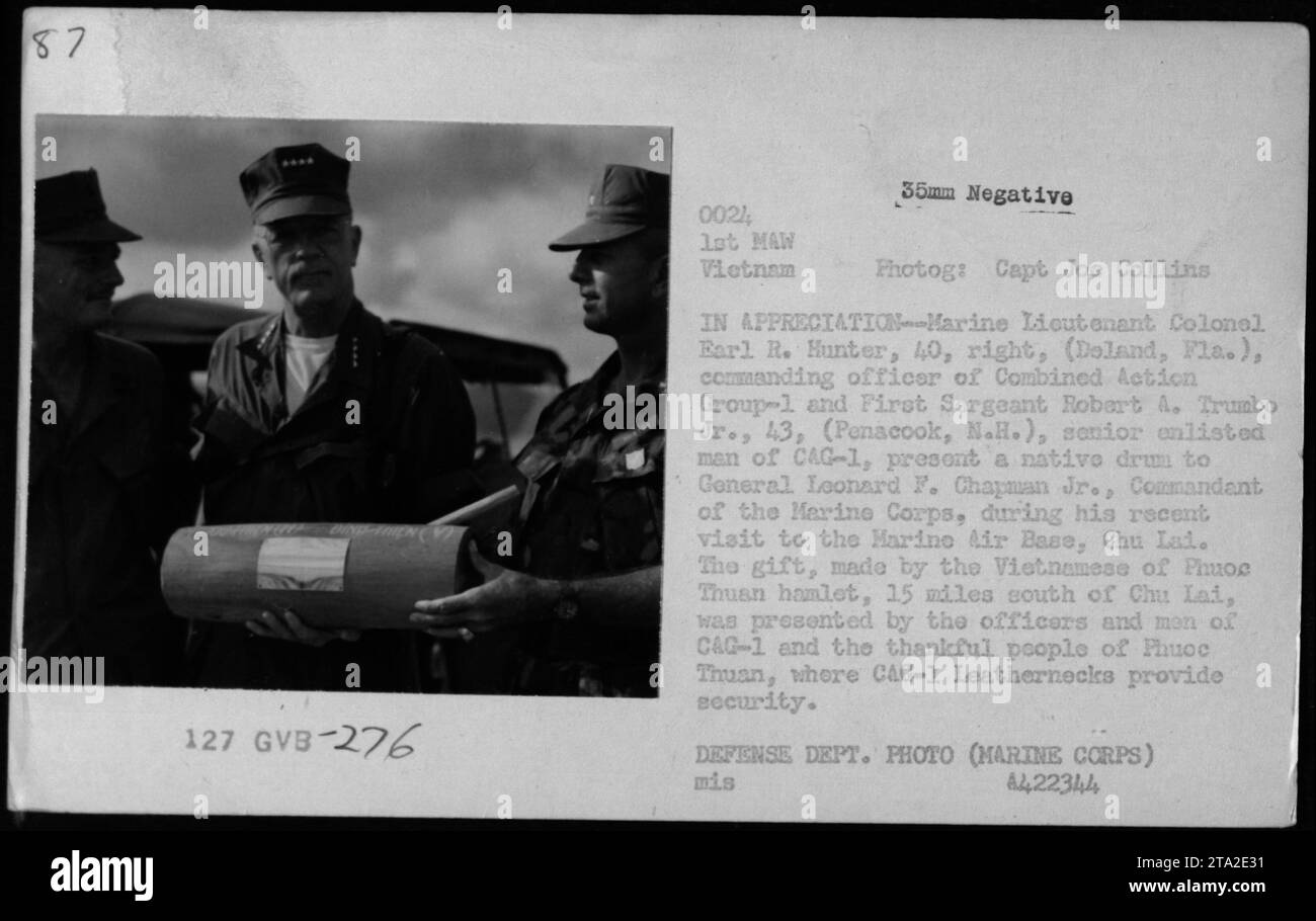 Marine Lieutenant Colonel Earl R. Hunter und First Sergeant Robert A. Trumbo Jr. präsentieren General Leonard F. Chapman Jr., Kommandant des Marine Corps, mit einer einheimischen Trommel während eines Besuchs auf der Marine Air Base in Chu Lai, Vietnam. Die Trommel war ein Geschenk des vietnamesischen Volkes des Dorfes Phuoc Thuan, das als Anerkennung für die Sicherheit der Offiziere und Männer von CAG-1 präsentiert wurde. Stockfoto