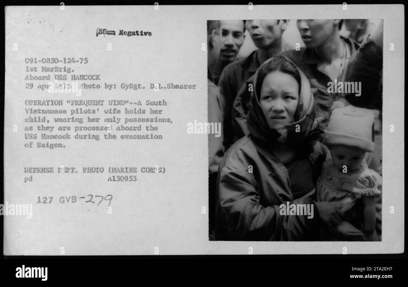 Eine südvietnamesische Frau, die Frau eines Piloten, trägt ihr Kind und Habseligkeiten an Bord der USS HANCOCK während der Evakuierung von Saigon am 29. April 1975 im Rahmen der Operation Frequent Wind. Stockfoto