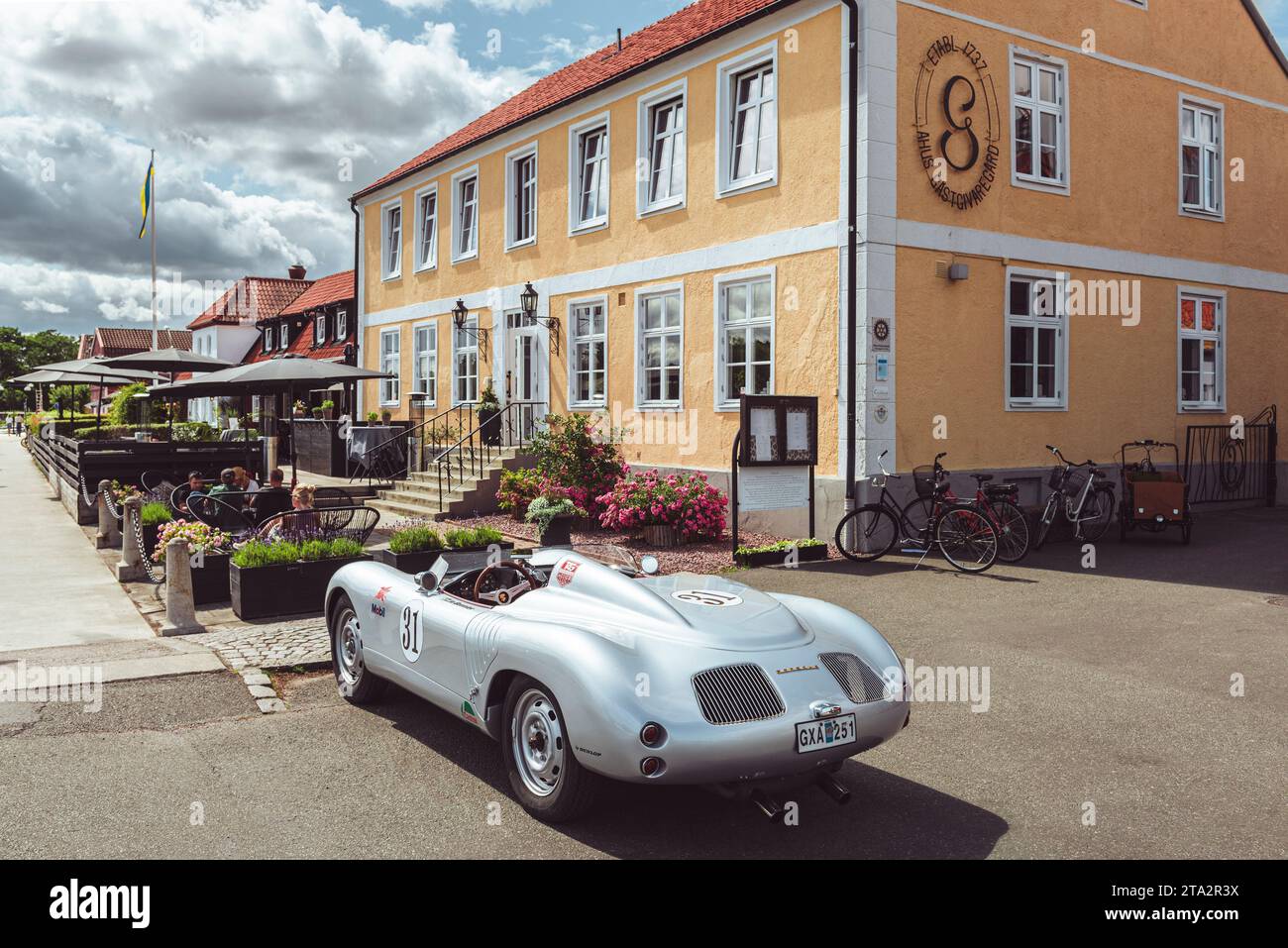 Eine silberfarbene Porsche 718 Spyder Nachbildung parkt vor der Terrasse vor einem Restaurant in aHUS im Sommer, Skåne, Schweden Stockfoto