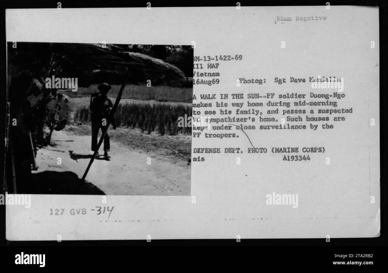 ARVN-Soldat Duong-NGO geht am Vormittag nach Hause, um seine Familie am 16. August 1969 in Vietnam zu besuchen. Als er das Haus eines mutmaßlichen VC-Sympathisanten passiert, beobachtet Duong-NGO es genau zusammen mit anderen PF-Soldaten. Das Foto wurde von Sgt. Dave Mendella als Teil der amerikanischen Militäraktivitäten während des Vietnamkriegs aufgenommen. Stockfoto