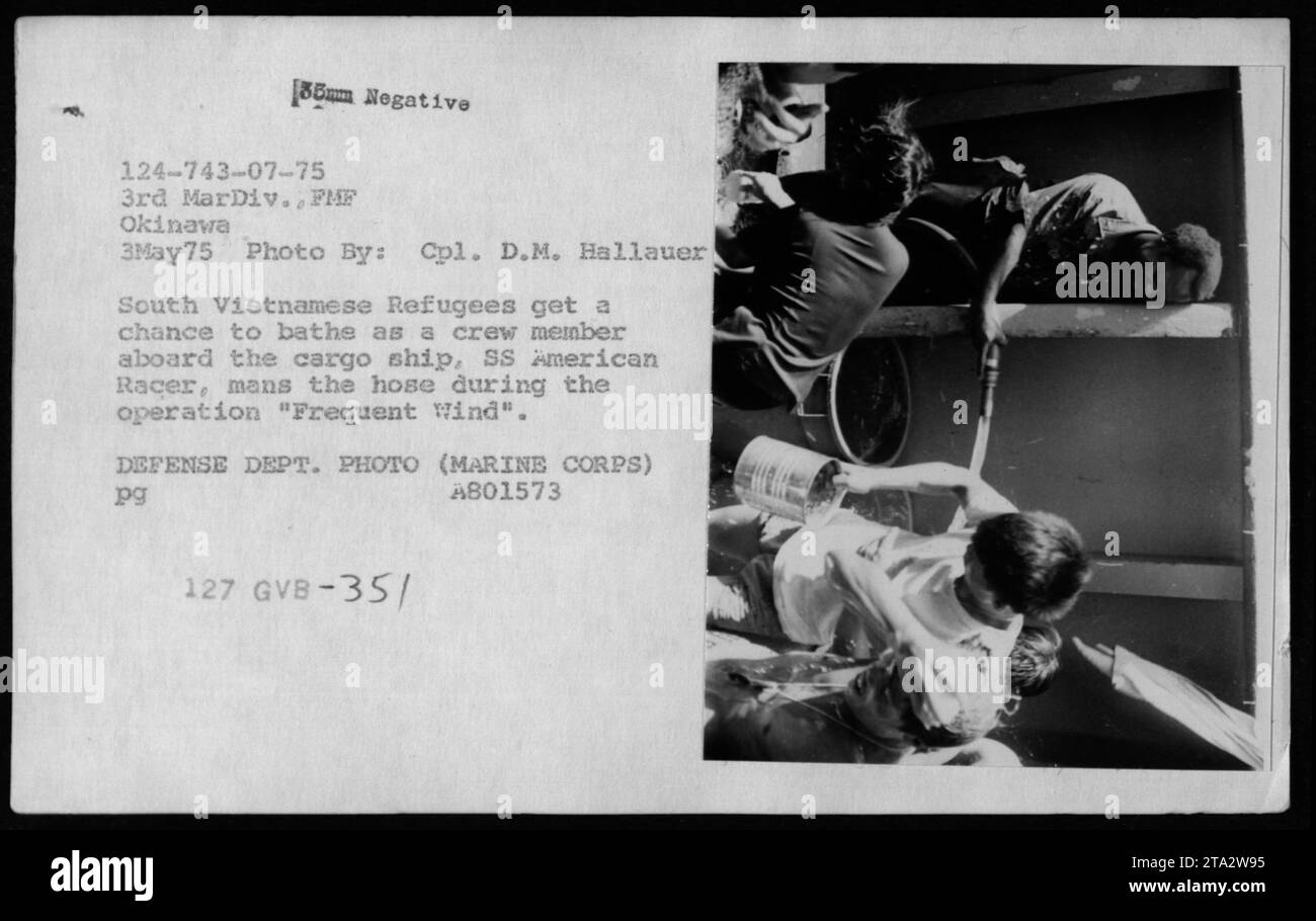 Südvietnamesische Flüchtlinge baden am 3. Mai 1975 an Bord der SS American Racer während der Operation Frequent Wind, wobei ein Besatzungsmitglied Wasser zur Verfügung stellt und humanitäre Hilfe während der Evakuierung der Flüchtlinge leistet. Stockfoto