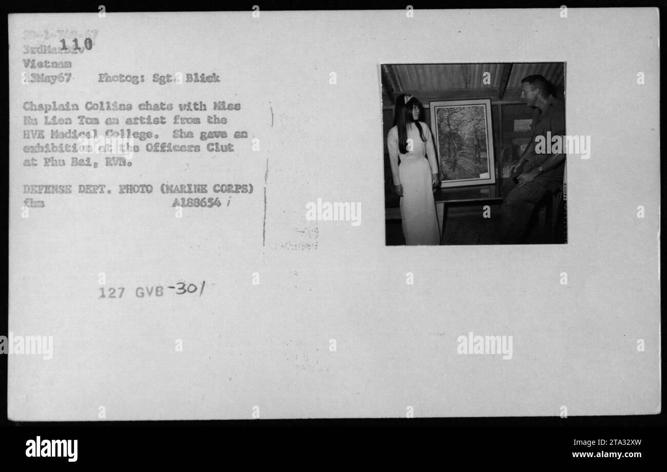 Kaplan Collins spricht mit der Künstlerin Miss Nu Lien Tom vom HVE Medical College während ihrer Ausstellung im Officers Club in Phu Bai, RVN. Das Foto wurde am 13. Mai 1967 aufgenommen und zeigt einen Moment der Interaktion zwischen dem Militär und vietnamesischen Zivilisten während des Vietnamkriegs. Stockfoto