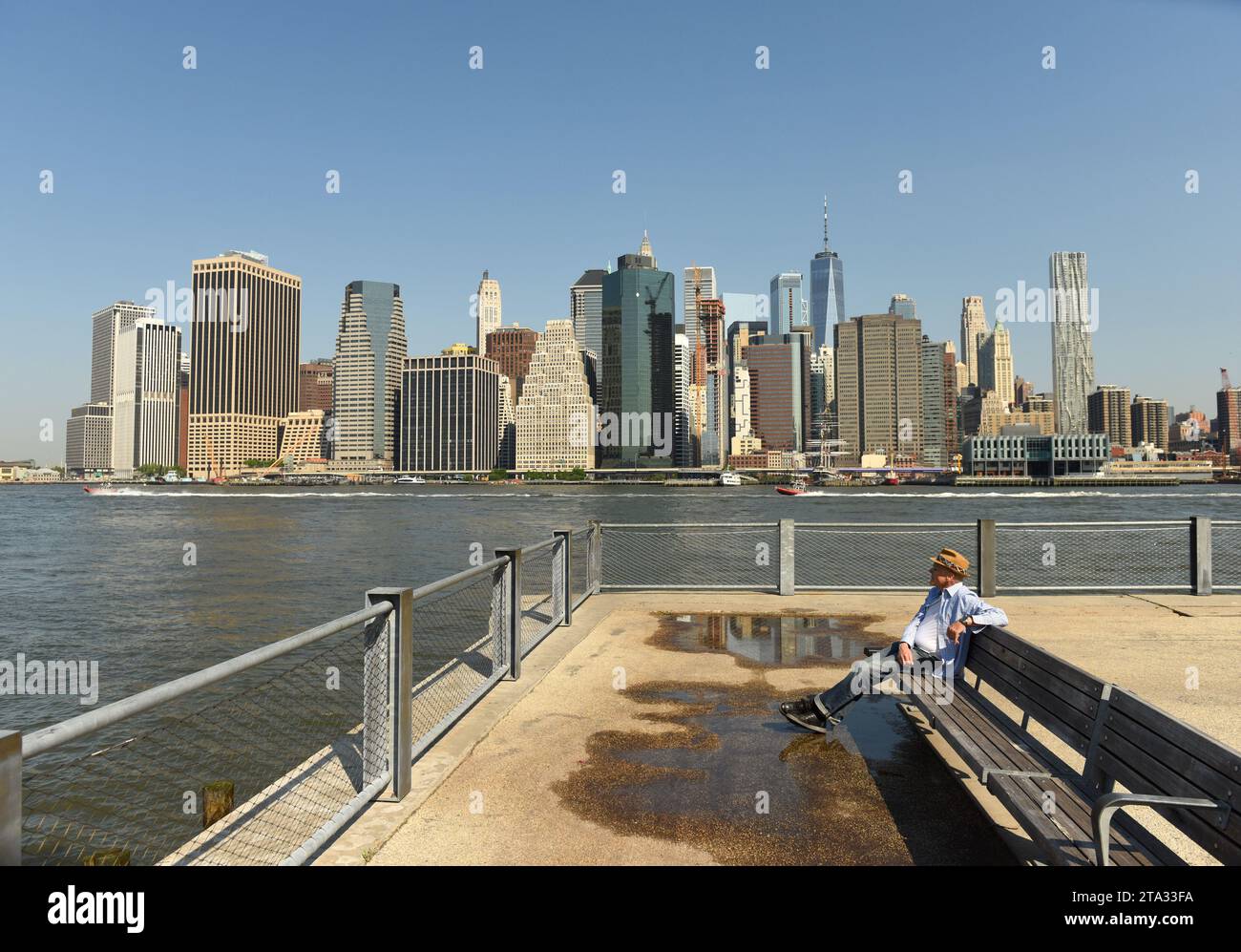 New York, USA - 25. Mai 2018: Ein Mann im Brooklyn Bridge Park mit Finanzviertel in Lower Manhattan im Hintergrund. Stockfoto