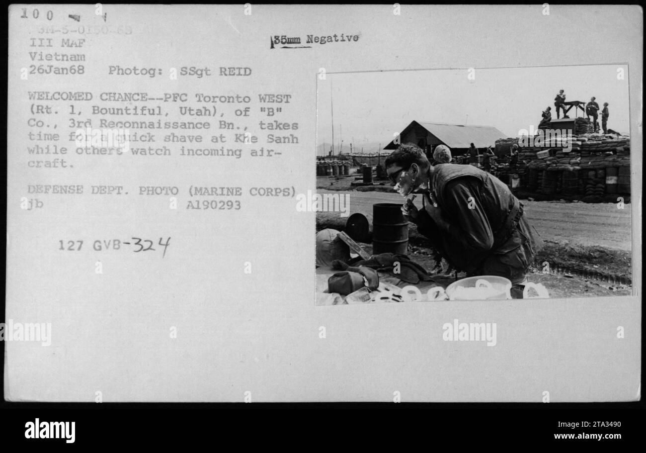 PFC Toronto westlich von 'B' Co., 3rd Reconnaissance Bn., nimmt sich einen Moment Zeit, um sich während des Vietnamkriegs in Khe Sanh zu rasieren, während andere Flugzeuge beobachten. Dieses Bild unterstreicht die Bedeutung der persönlichen Hygiene auch in Zeiten militärischer Aktivitäten. Das Foto wurde am 26. Januar 1968 von SSgt Reid aufgenommen und ist ein Foto des Verteidigungsministeriums. Stockfoto