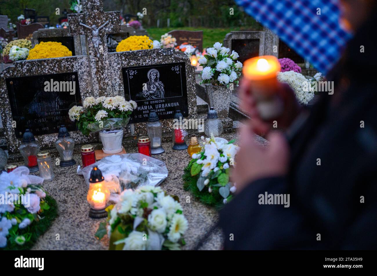 Die Gläubigen legen Blumen und Kerzen und beten für die Verstorbenen auf ihrem Grab. Stockfoto