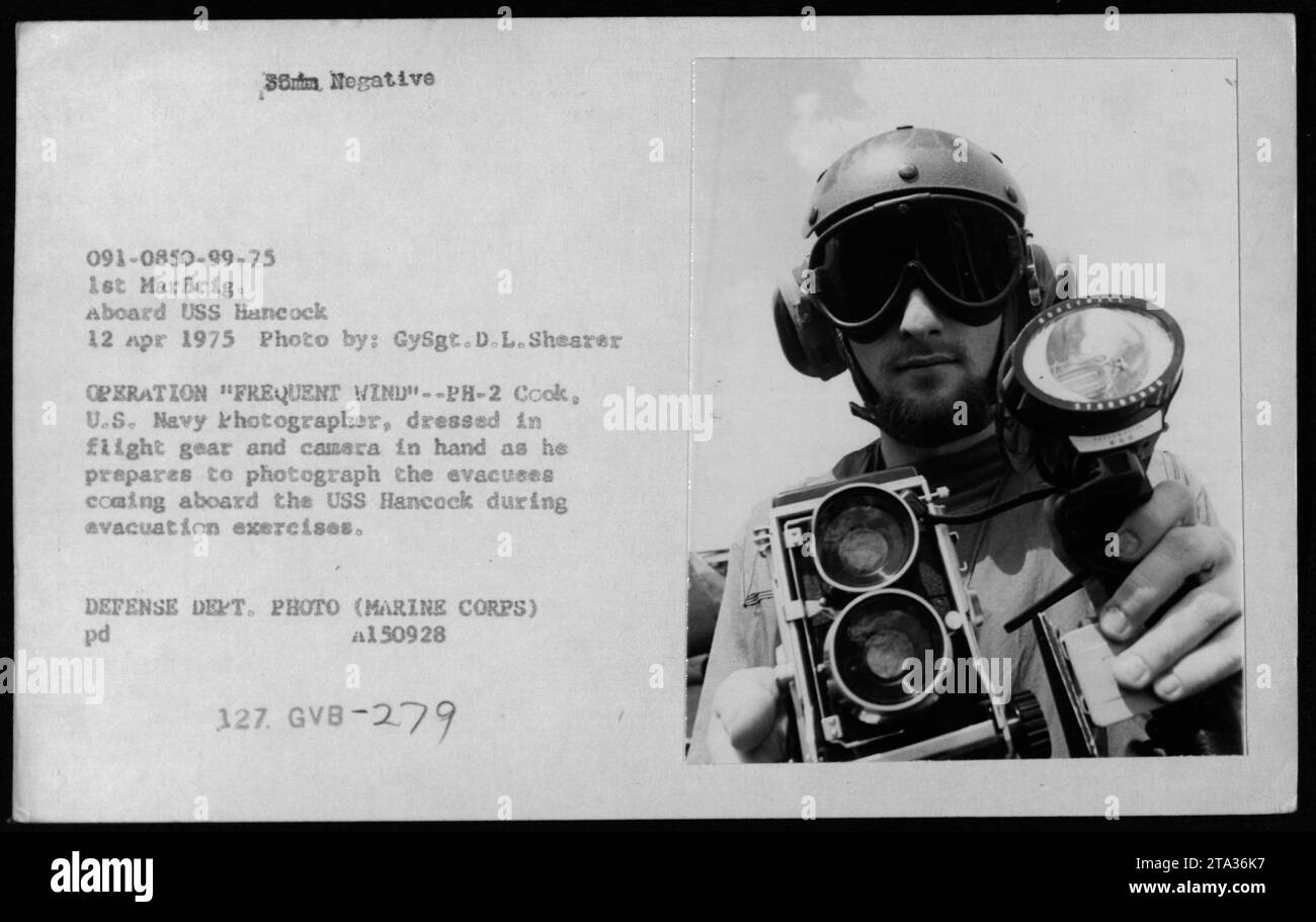 GySgt D.L. Shearer, ein Fotograf der US Navy, bereitet sich darauf vor, Evakuierten, die an Bord der USS Hancock während der Operation Frequent Wind am 12. April 1975 im Rahmen von Evakuierungsübungen zu fotografieren. Stockfoto