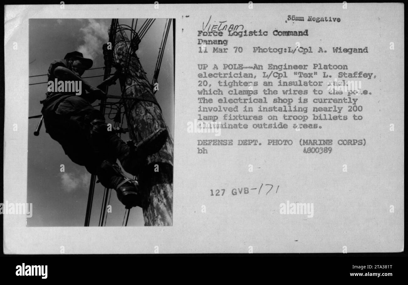 Am 11. März 1970 verspannt L/CPL Tex L. Staffey, ein Elektriker im Engineer Platoon, ein Isolatorgestell, das Kabel mit einem Pol des Force Logistic Command in Danang, Vietnam, verbindet. In der Elektrowerkstatt werden 200 Lampenfassungen an Truppenstufen für Außenbeleuchtung installiert. Fotodokumente Wartungsvorgänge. Stockfoto