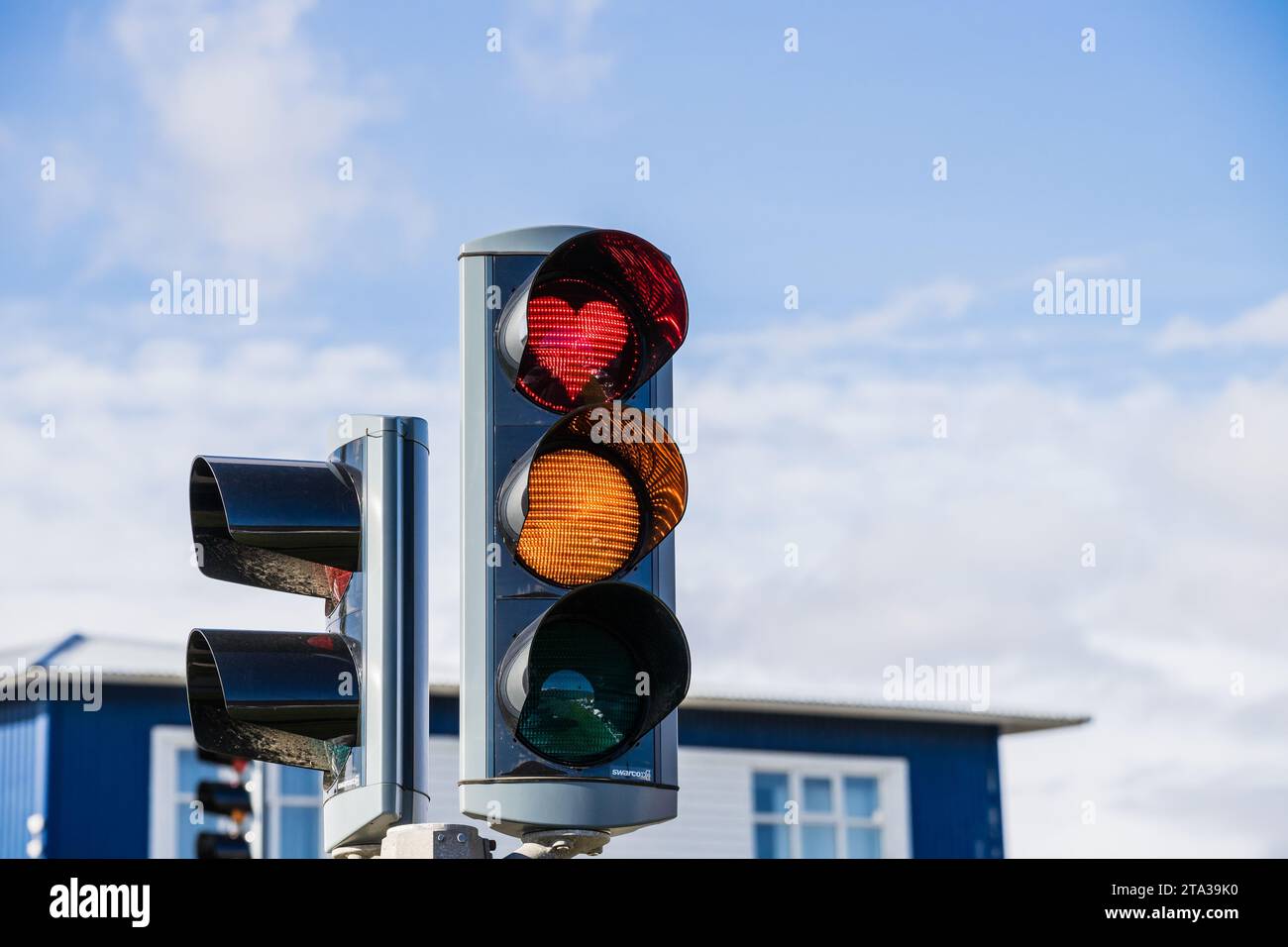 Eine leuchtende rote, gelbe und grüne Ampel mit einer herzförmigen Reflexion im Glas Stockfoto