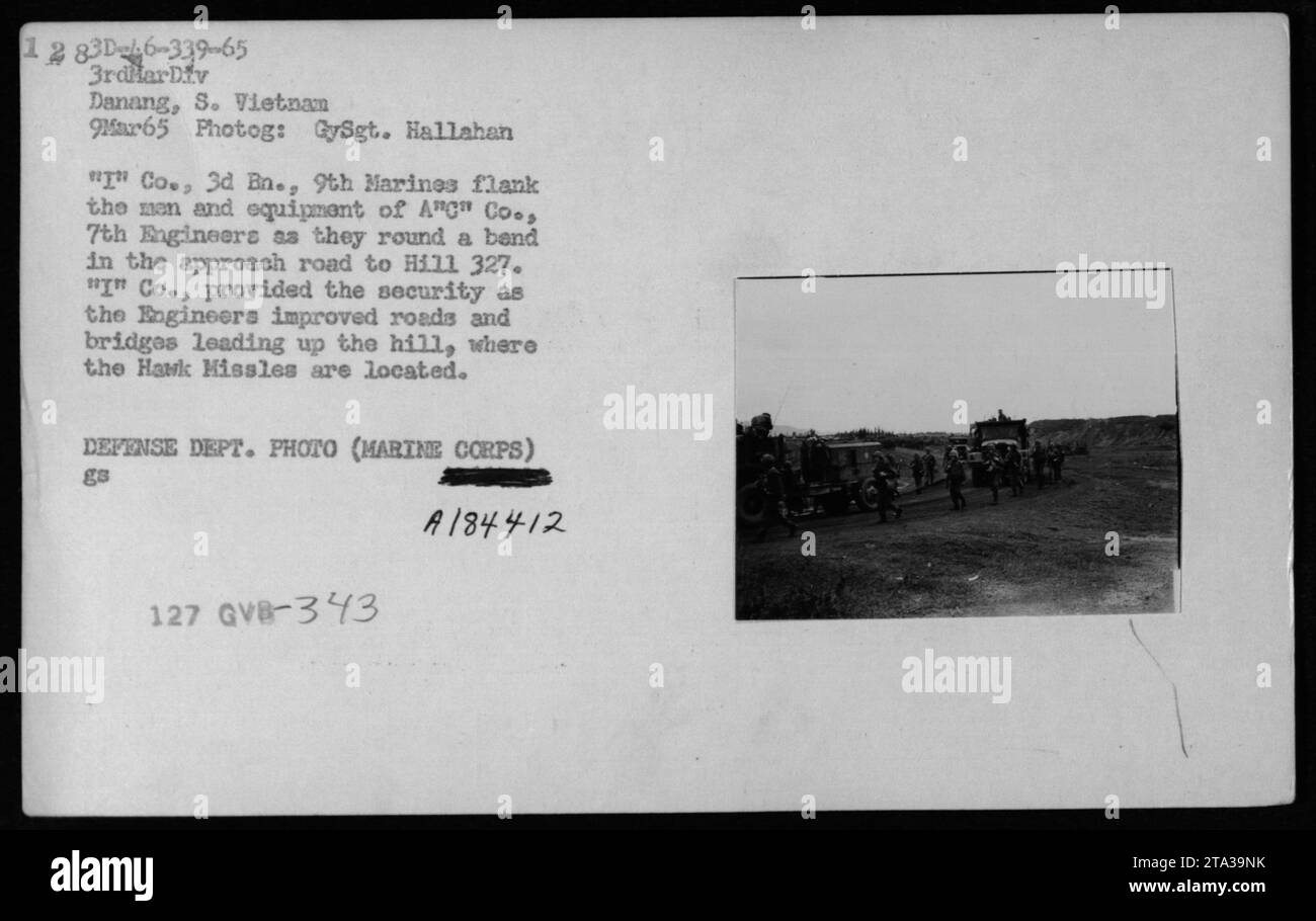 Männer und Ausrüstung von Ang Co., 7. Ingenieure umrunden eine Kurve in einer Straße, während sie flankiert werden von 'T' Co., 3. Mrz., 9. Marines in Danang, Vietnam am 9. März 1965. Die Ingenieure bauten Straßen und Brücken auf, die zum Hügel 327 führten, wo sich die Hawk-Raketen befinden.“ Stockfoto