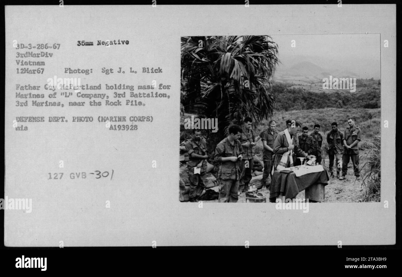Pater Guy McPartland leitet am 13. Februar 1967 eine Messe für L Company, 3rd Battalion, 3rd Marines in der Nähe des Felsenpfahls in Vietnam, die die religiöse Praxis und die moralische Unterstützung der Marines veranschaulicht. Stockfoto
