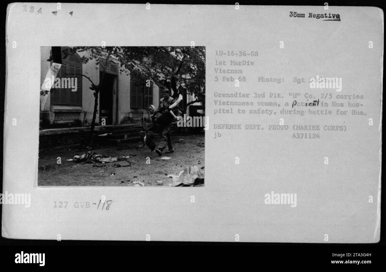 Während der Schlacht um Hue City am 5. Februar 1968 machte Sergeant Dickmen von der 1. Marine-Division in Vietnam dieses Foto. Auf dem Bild ist ein Marine des 3. Platoon, 'H' Kompanie, 2/5 Regiment, zu sehen, der vietnamesische Frauen in Sicherheit bringt. Dieser Akt fand mitten in der Schlacht statt, als die Marines für die Sicherung der Stadt kämpften. Das Foto wurde auf einem 35 mm-negativ mit dem Lichtbildcode 1D-16-36-68 aufgenommen. Stockfoto