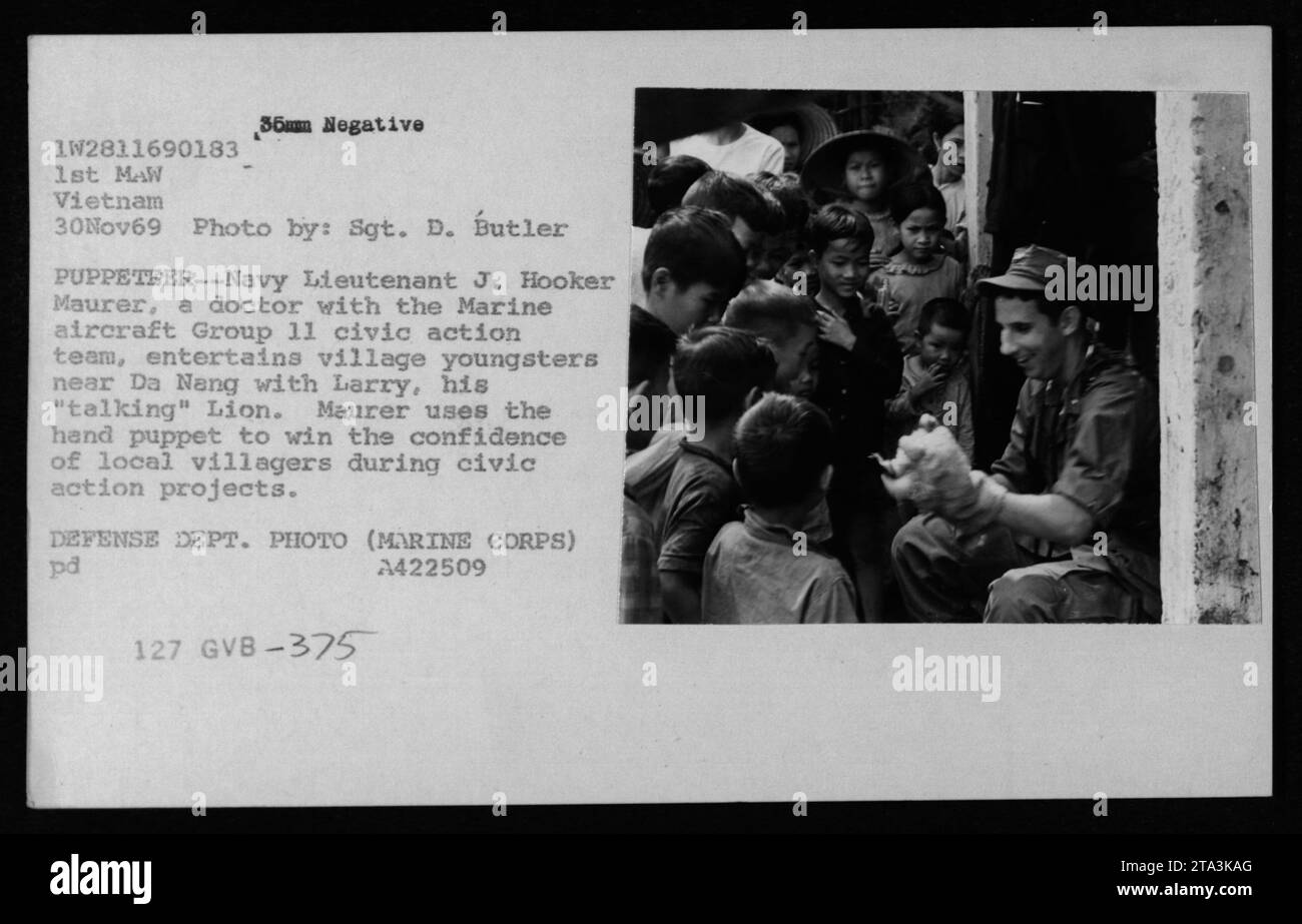 Vietnamesische Zivilisten in einem Dorf in der Nähe von da Nang werden von Marineleutnant J. Hooker Maurer unterhalten, einem Arzt des zivilen Action-Teams der Marine Aircraft Group 11. Er benutzt eine Handpuppe namens Larry, der mit ihm „spricht“, um sich bei Bürgeraktionen mit den Dorfbewohnern in Verbindung zu setzen und das Vertrauen dieser Menschen zu gewinnen. Dieses Foto wurde am 30. November 1969 von Sgt. D. Butler aufgenommen. Stockfoto