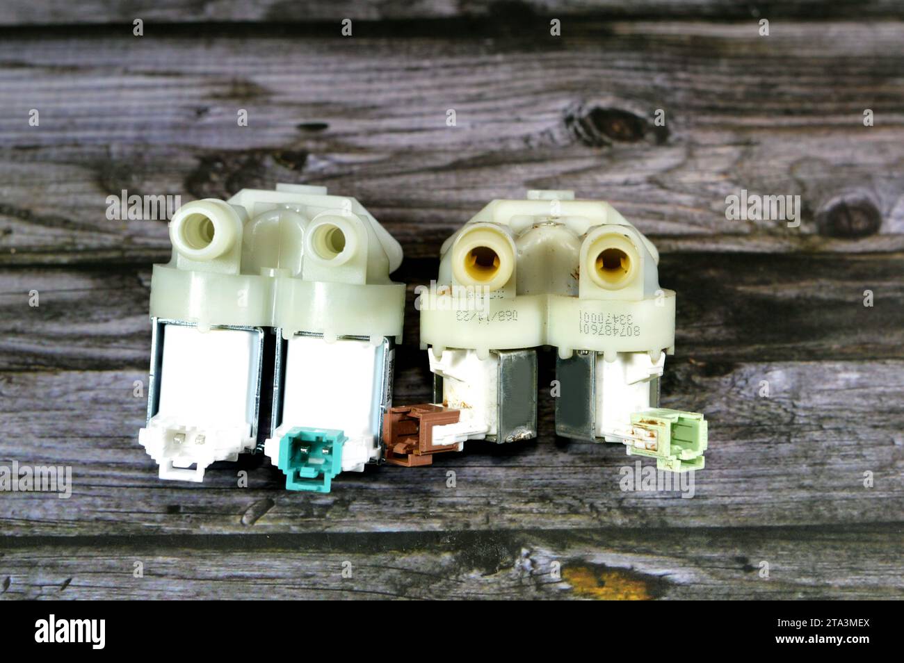 Ein defektes und ein neues Einlasswasserventil der automatischen elektrischen Waschmaschine, ein Magnetventil, ein elektromechanisch betätigtes Ventil, das Wasser steuert Stockfoto