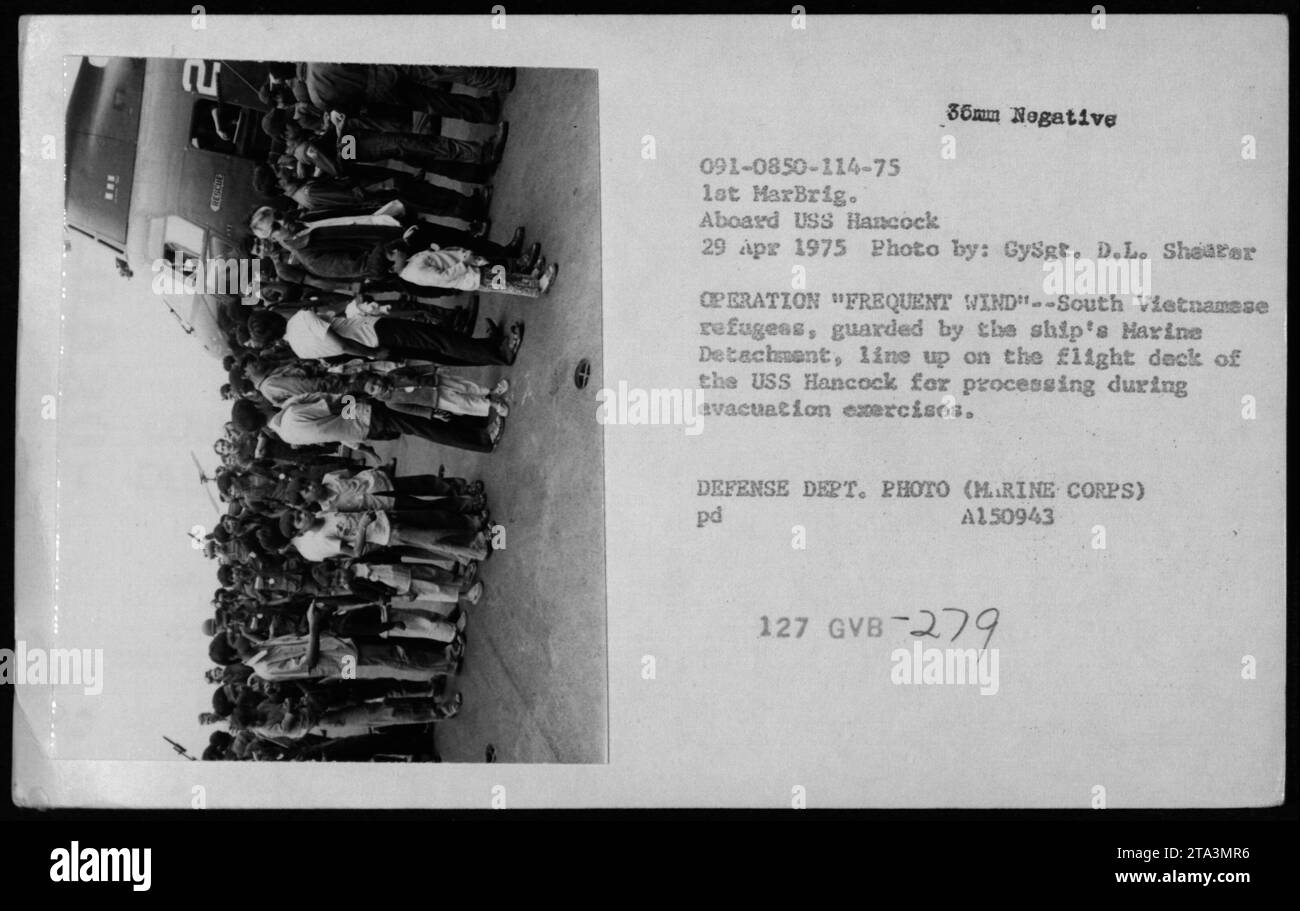 Südvietnamesische Flüchtlinge, die von der Marine-Abteilung des Schiffes bewacht werden, stehen auf dem Flugdeck der USS Hancock zur Bearbeitung während der Evakuierungsübungen an. Dieses Foto wurde während der Operation Frequent Wind am 29. April 1975 im Rahmen der Evakuierung von Phnom Penh und Saigon aufgenommen. Das Bild wurde von GySgt aufgenommen. D.L. Shearer. Stockfoto