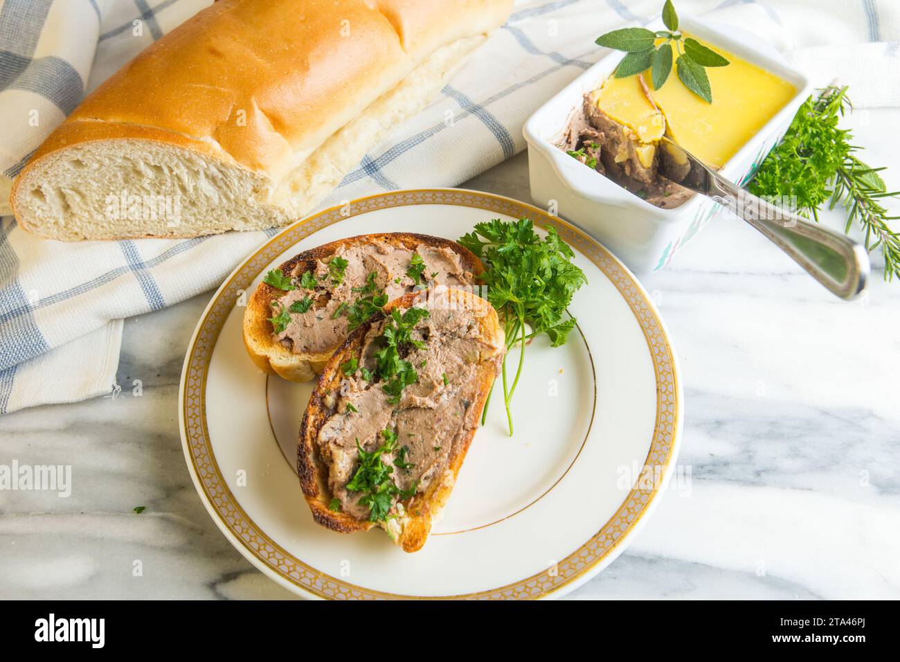 Hausgemachte Hühnerleber-Pastete auf geröstetem Weißbrot und serviert auf einem Teller mit Petersilie garniert Stockfoto
