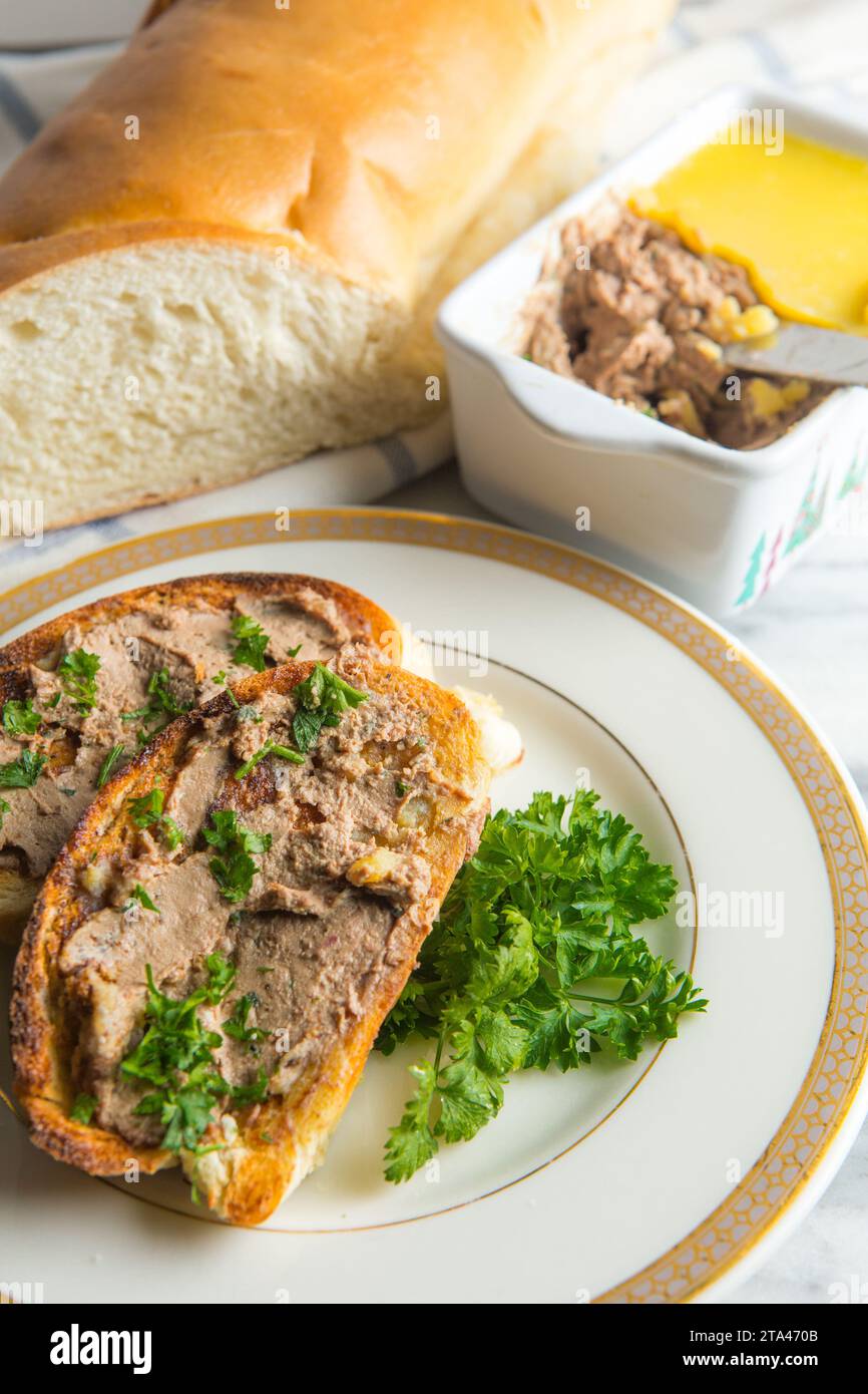 Hausgemachte Hühnerleber-Pastete auf geröstetem Weißbrot und serviert auf einem Teller mit Petersilie garniert Stockfoto