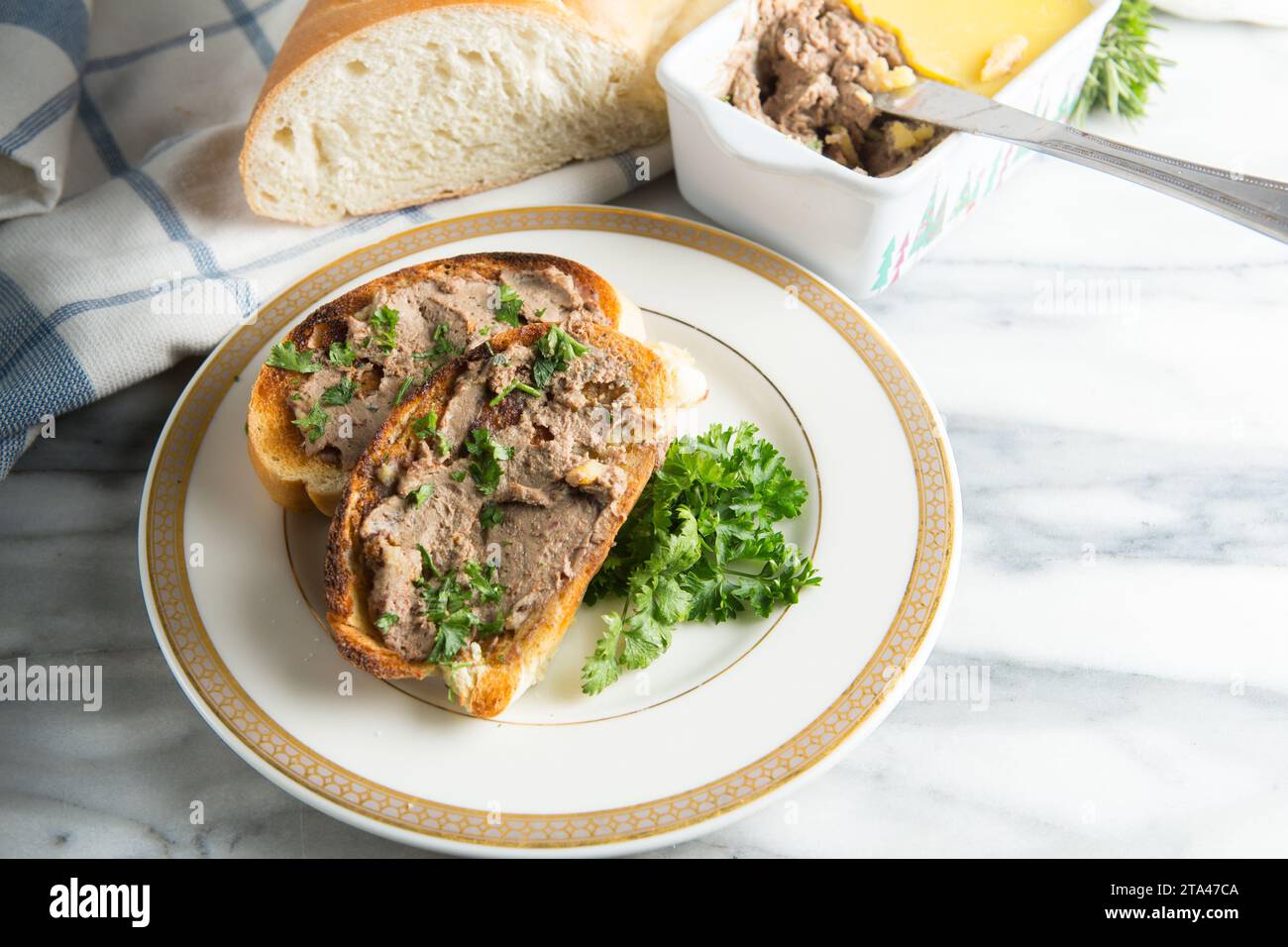 Hausgemachte Hühnerleber-Pastete auf geröstetem Weißbrot und serviert auf einem Teller mit Petersilie garniert Stockfoto