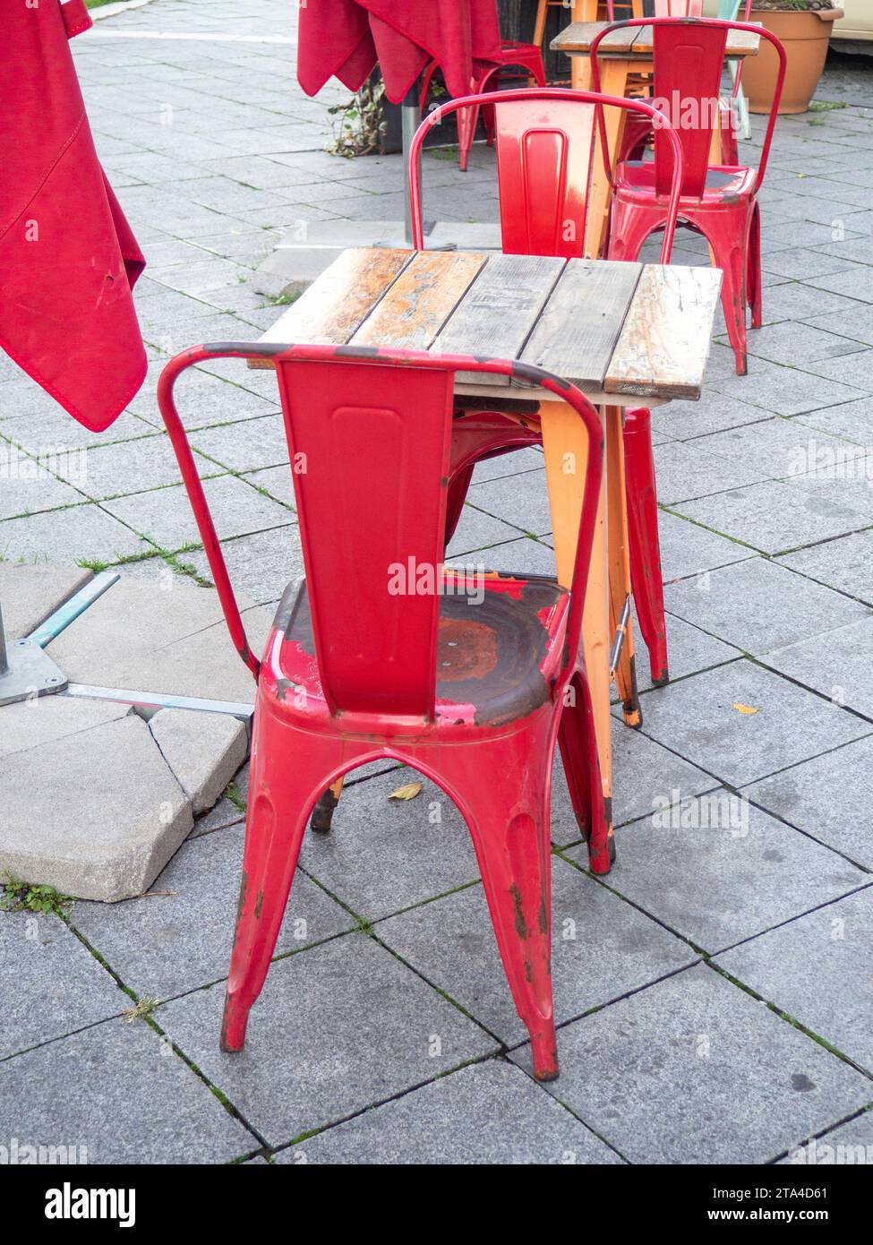 Alte schäbige Tische und Stühle in einem Café. Es gibt keine Gäste im Café auf der Straße. Alte Möbel auf der Straße. Stockfoto