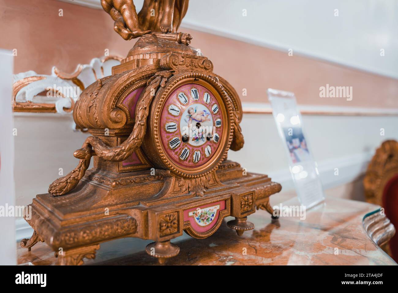 Elegantes traditionelles Wohnzimmer mit kunstvoll verzierten braunen und goldenen Uhr auf Marmortisch. Stockfoto