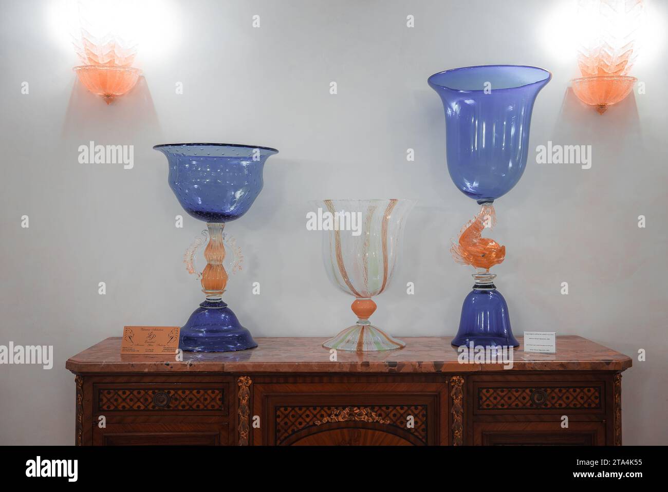 Stilvolle blaue und orange Glasvasen auf Holzkommode in elegantem Display Stockfoto