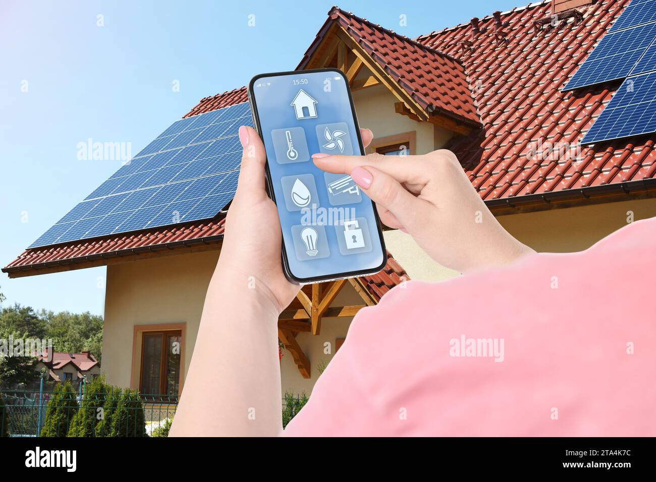 Frau mit Smart Home Control System per Handy in der Nähe von Haus draußen, Nahaufnahme Stockfoto