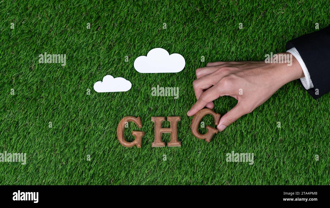 Ordnen Sie hölzernen Alphabettext in THG auf biophilem Hintergrund mit dem Treibhausgase-Symbol als Öko-Symbol an, um die Botschaft für das Treibhausgase zu fördern Stockfoto