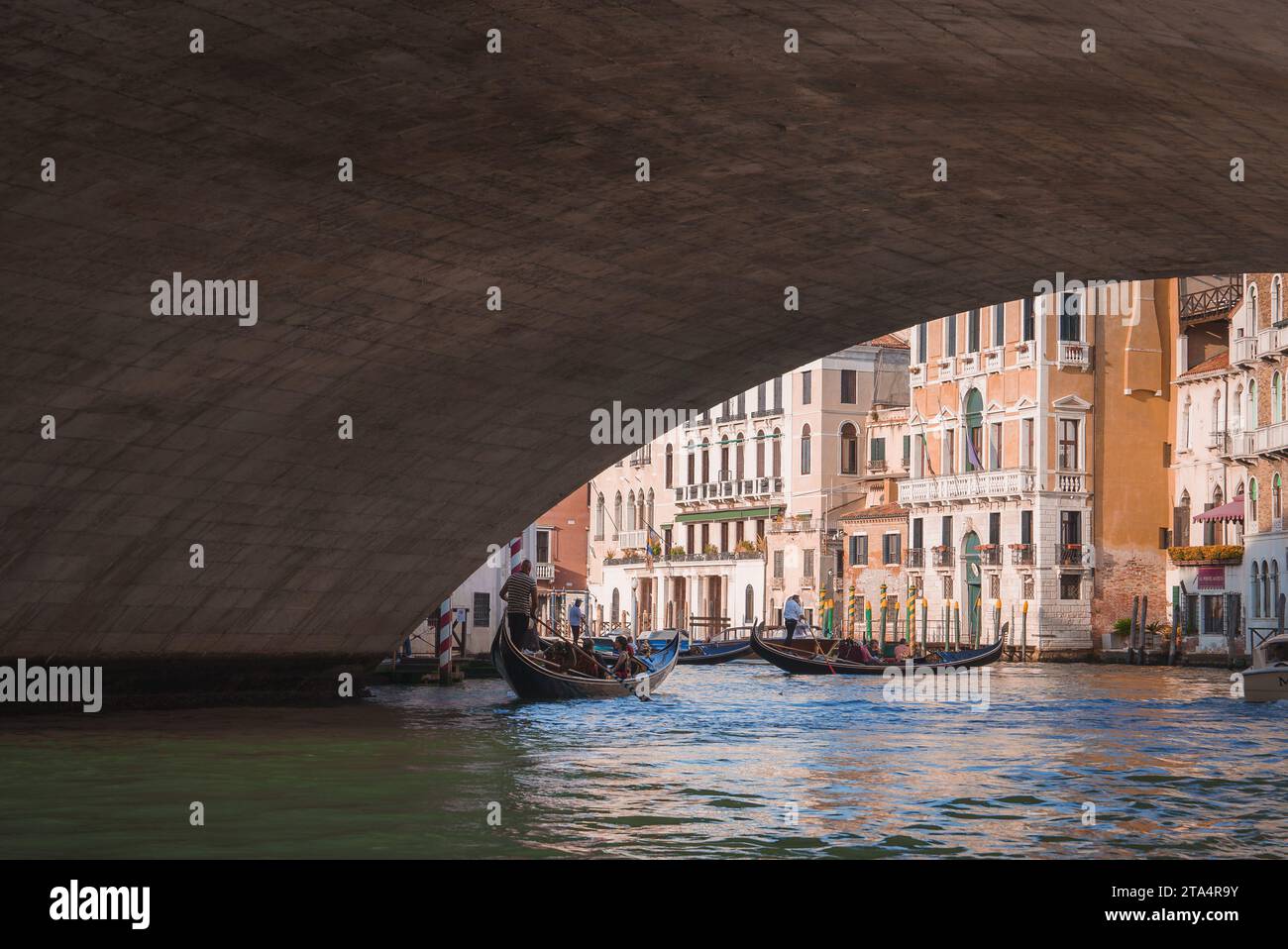 Malerische Gondelfahrt durch Venedig unter der Bogenbrücke mit Reflexionen im Wasser Stockfoto