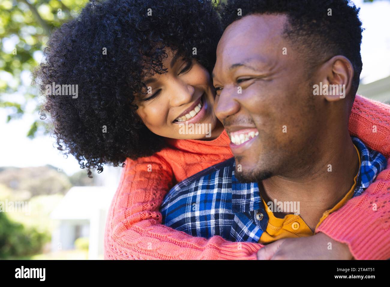 Glückliches afroamerikanisches Paar reitet Huckepack im sonnigen Garten, Kopierraum. Draußen, Ausdruck, Liebe, Zweisamkeit und Natur, unveränderlich. Stockfoto