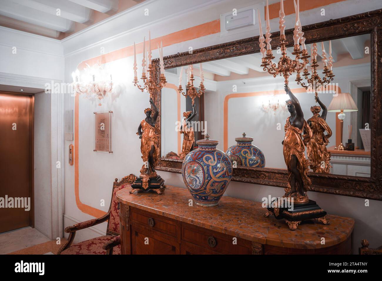 Stilvolles und elegantes Wohnzimmer mit verzierten Möbeln, Spiegel und Kronleuchter in neutralen Farben Stockfoto