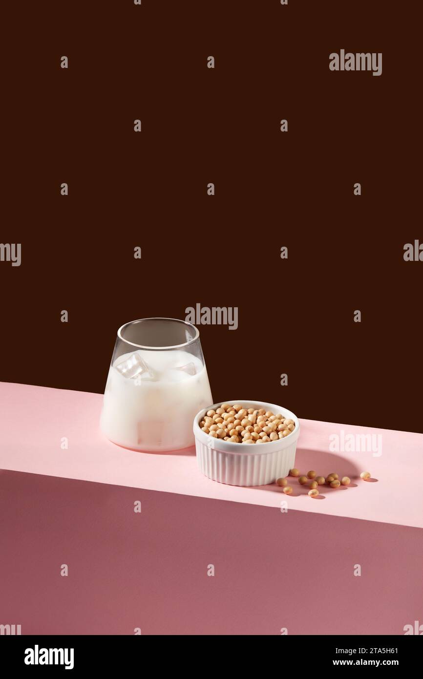 Minimale Szene einer Tasse frischer Milch, dekoriert mit vielen Sojabohnen in einer weißen Schüssel. Nüsse sind eine große Quelle für mehrere Nährstoffe, einschließlich vit Stockfoto