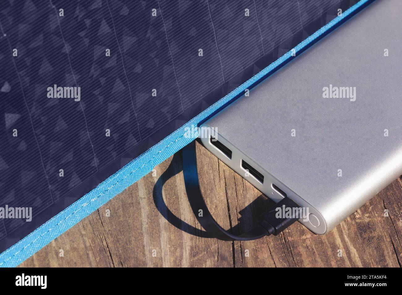 Powerbank-Ladevorgang Mit Tragbarem Solarmodul. Elektrische Gadgets Stromversorgung Für Campingplatz. USB-Kabel mit Akkumulator verbunden. Stockfoto