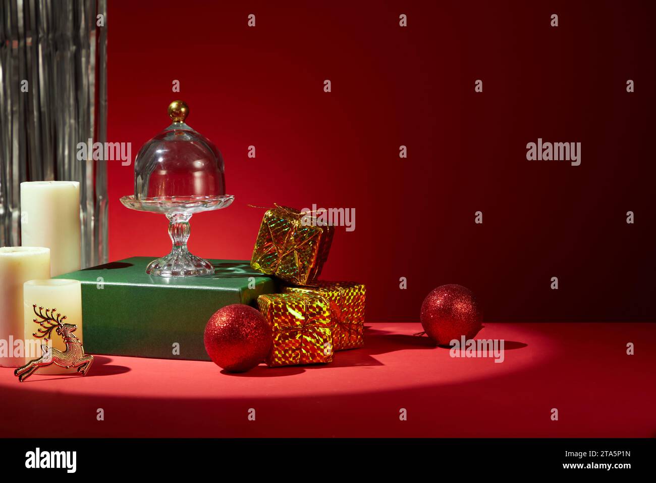Ideen zur Dekoration des Weihnachtstisches in roten Tönen. Farbenfrohe Dekorationen sind auf dem Tisch platziert, Perlen, duftende Kerzen Geschenkboxen sind mit dekoriert Stockfoto