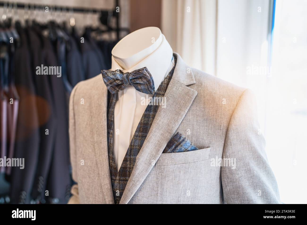 Schaufensterpuppe in einem hellgrauen Anzug mit karierter Fliege und passendem Taschenquadrat Stockfoto