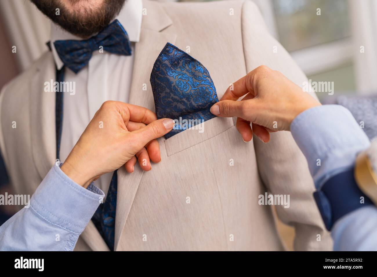 Nahaufnahme eines Schneiders, der ein blau gemustertes Taschenquadrat in eine Anzugsjacke legt Stockfoto