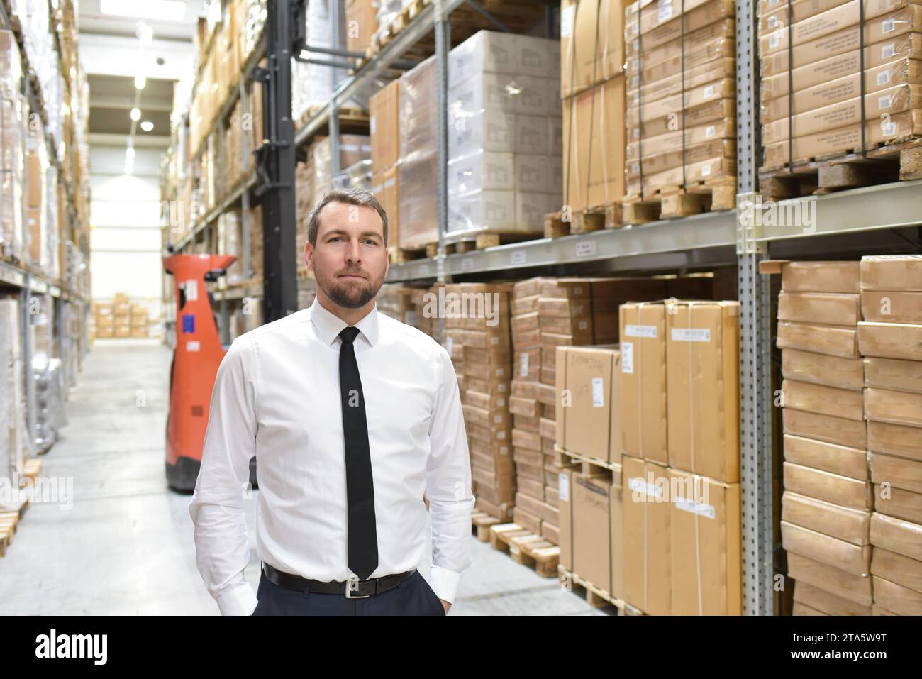 Portrait freundlicher Geschäftsmann/Manager im Anzug, der im Lager eines Unternehmens arbeitet Stockfoto