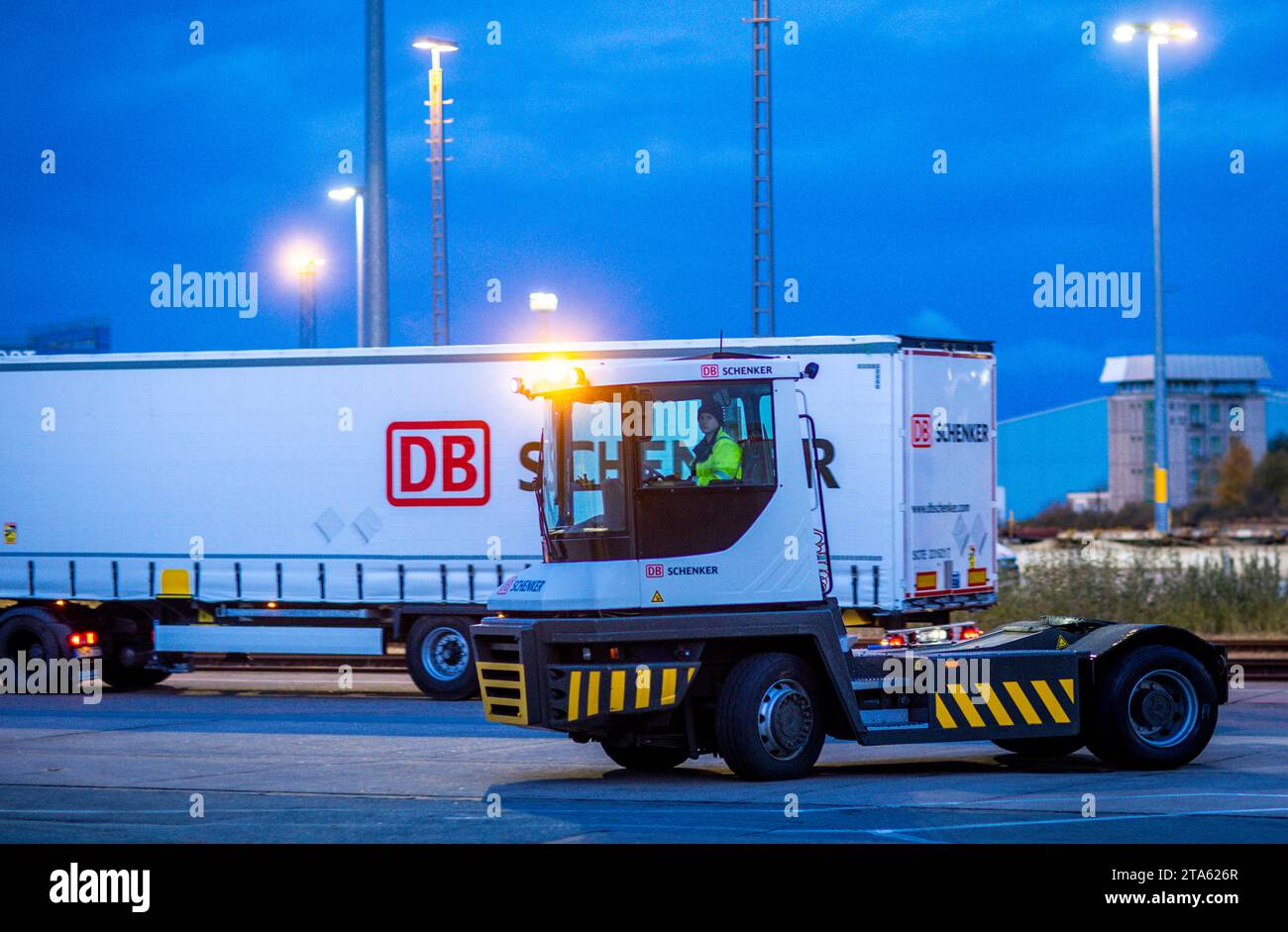 Rostock, Deutschland. November 2023. Die Zugmaschine eines DB Schenker Logistikunternehmens ist morgens auf dem Gelände des Logistikzentrums im Seehafen unterwegs und transportiert Anhänger zu den Entladestationen. Die Logistikgesellschaft der Deutschen Bahn betreibt mehrere Logistikzentren in Mecklenburg-Vorpommern. Quelle: Jens Büttner/dpa/Alamy Live News Stockfoto