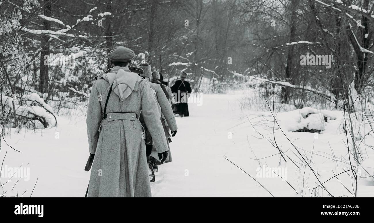 Armee auf dem Marsch. Männer, die als Soldaten der Weißen Garde der kaiserlichen russischen Armee im russischen Bürgerkrieg gekleidet sind, marschieren durch den verschneiten Winterwald. Historisch Stockfoto