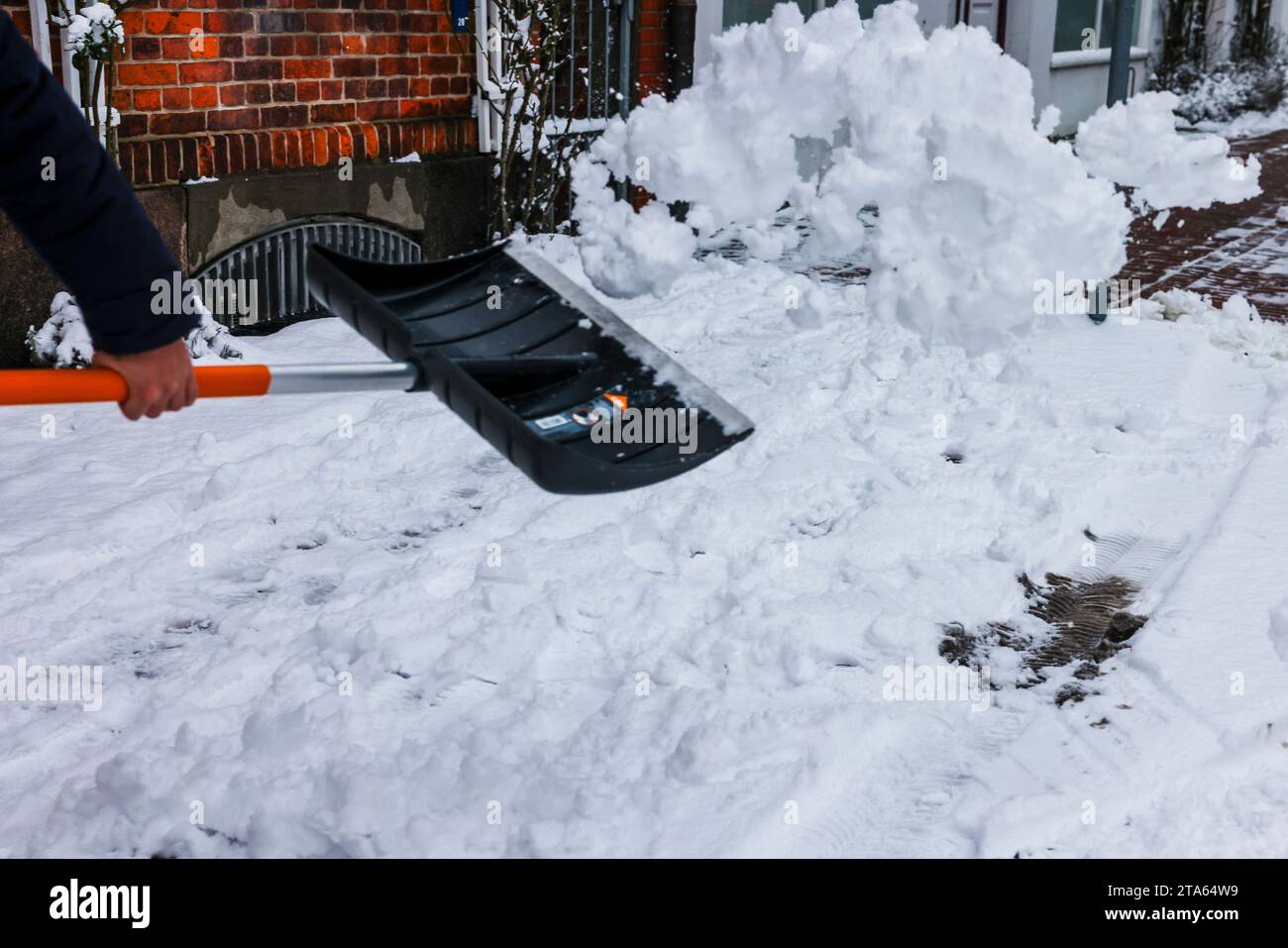 Rendsburg, Deutschland. November 2023. Ein Mann entfernt Schnee von einem Bürgersteig im Stadtzentrum mit einer Schaufel. Frank Molter/dpa/Alamy Live News Stockfoto