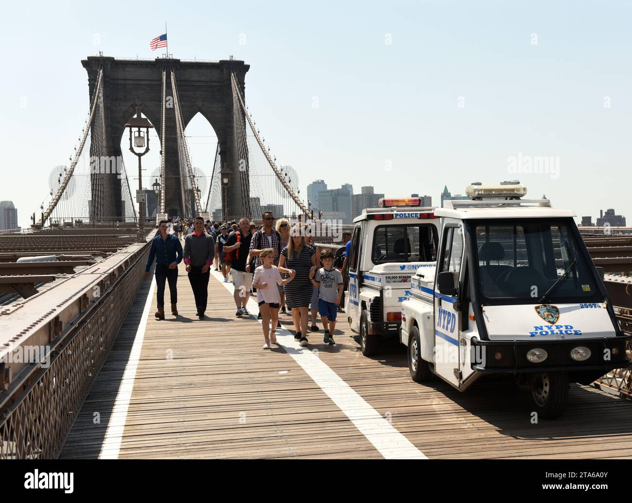 New York, USA - 25. Mai 2018: Polizeiauto und Menschenmenge auf der Brooklyn Bridge mit Finanzviertel in Lower Manhattan im Hintergrund. Stockfoto