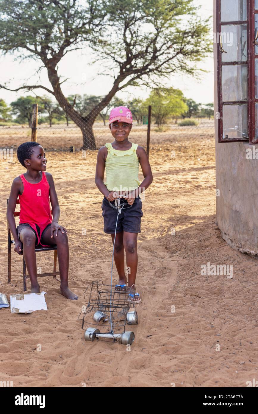 afrikanische Dorfkinder spielen im Hof mit einem Spielzeugauto aus Draht Stockfoto