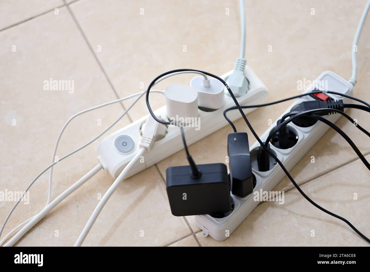 Überlastete Stromversorgungsplatinen. Steckdosenleisten mit verschiedenen Steckern auf weißem Boden. Konzept der Gefahr Gefahr Überlaststrom elektrisch Stockfoto
